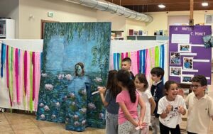 Bambini in piedi davanti ad un pannello con la riproduzione di un quadro