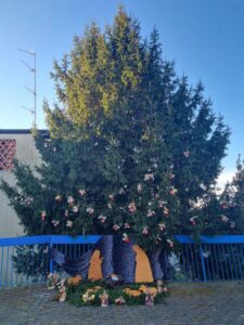 Albero in giardino con decorazioni natalizie e presepe